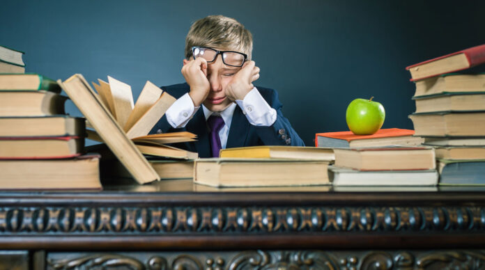 Schoolboy in stress or depression at school classroom