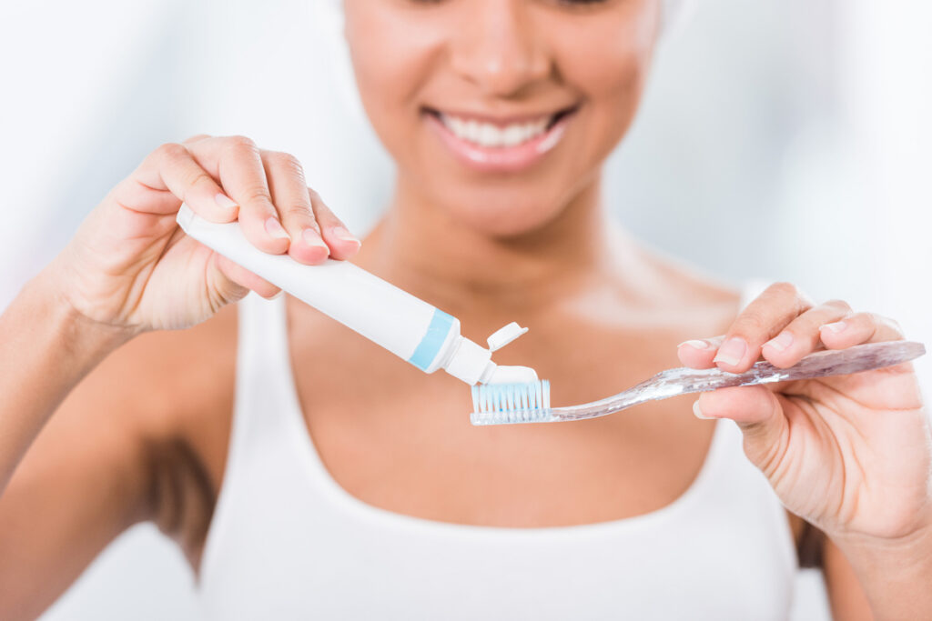 selective focus of young woman putting toothpaste on toothbrush tstpp Женщина, наносящая зубную пасту на зубную щетку