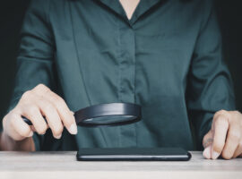 Вы уже пользуетесь ИИ, просто не замечаете этого Человек, держащий увеличительное стекло над мобильным телефоном на столе