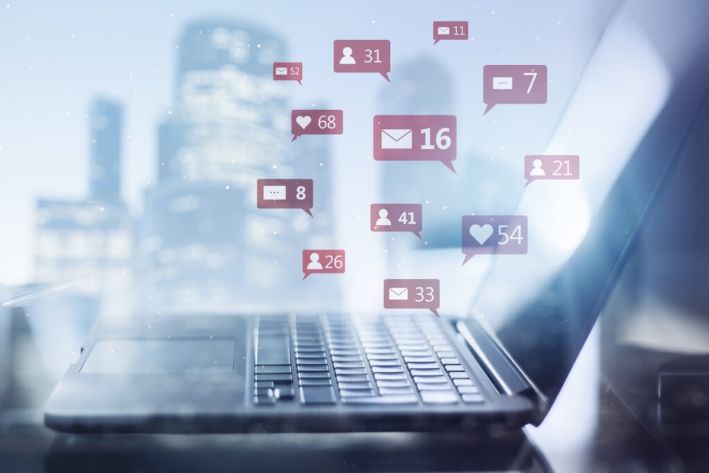 Ноутбук с иконками социальных сетей на размытом ярком городском фоне
