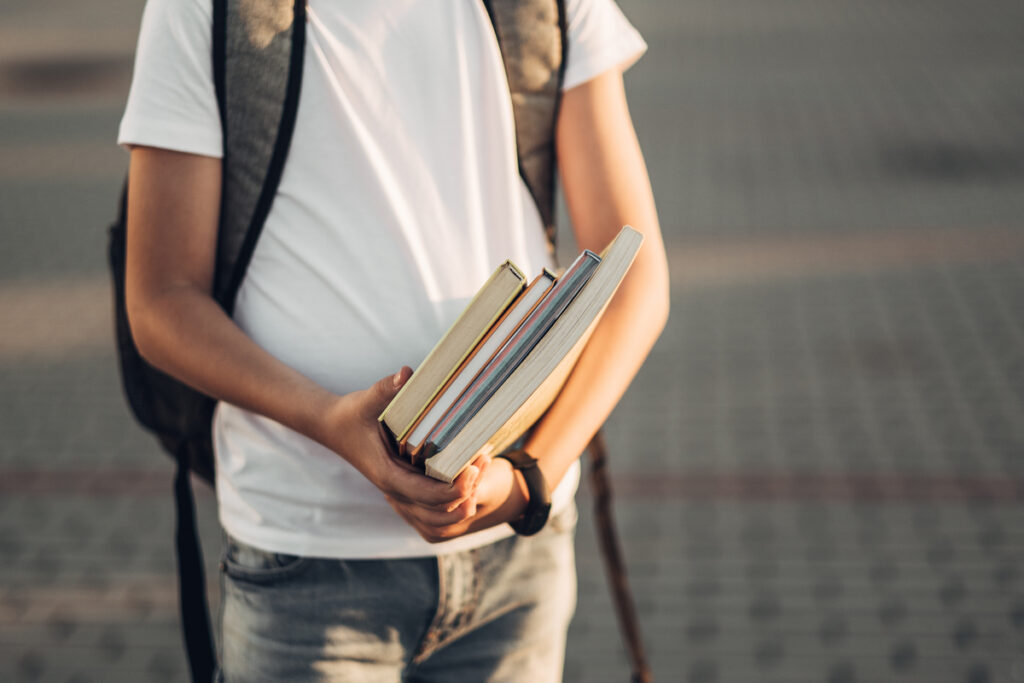 Подросток с книгами и рюкзаком, готовый к школе