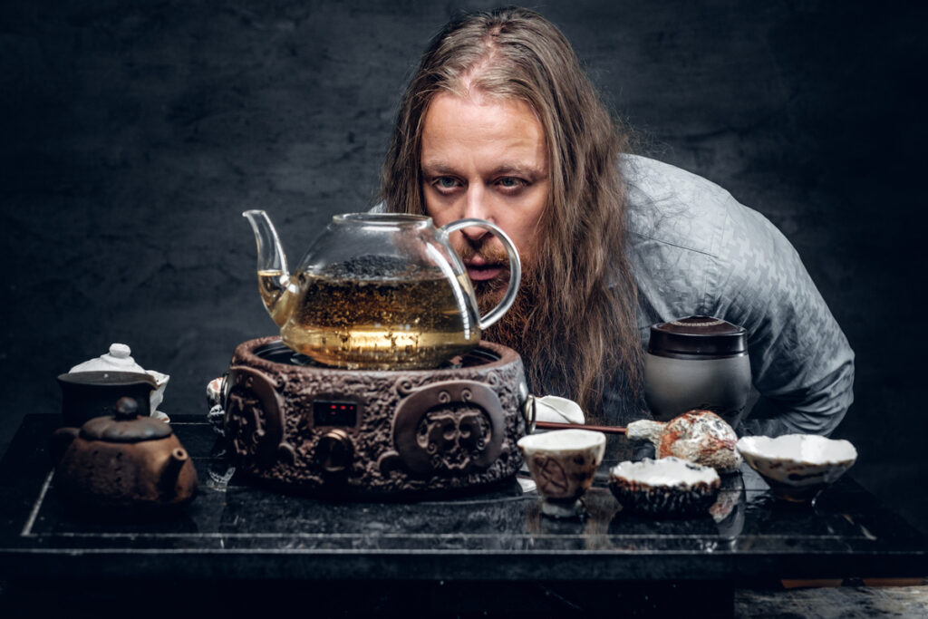 Bearded male with long hair preparing tea - ekbonline мужчина следит за тем, как заваривается чай