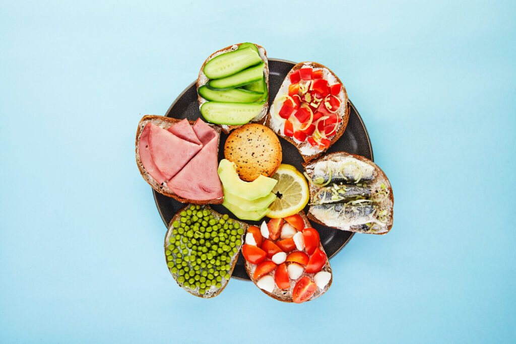 Assorted open-faced sandwiches sandwiches with slices of sourdough with various fillings on a blue background top view Flat lay Copy space - infovzor Ассорти сэндвичей на тарелке