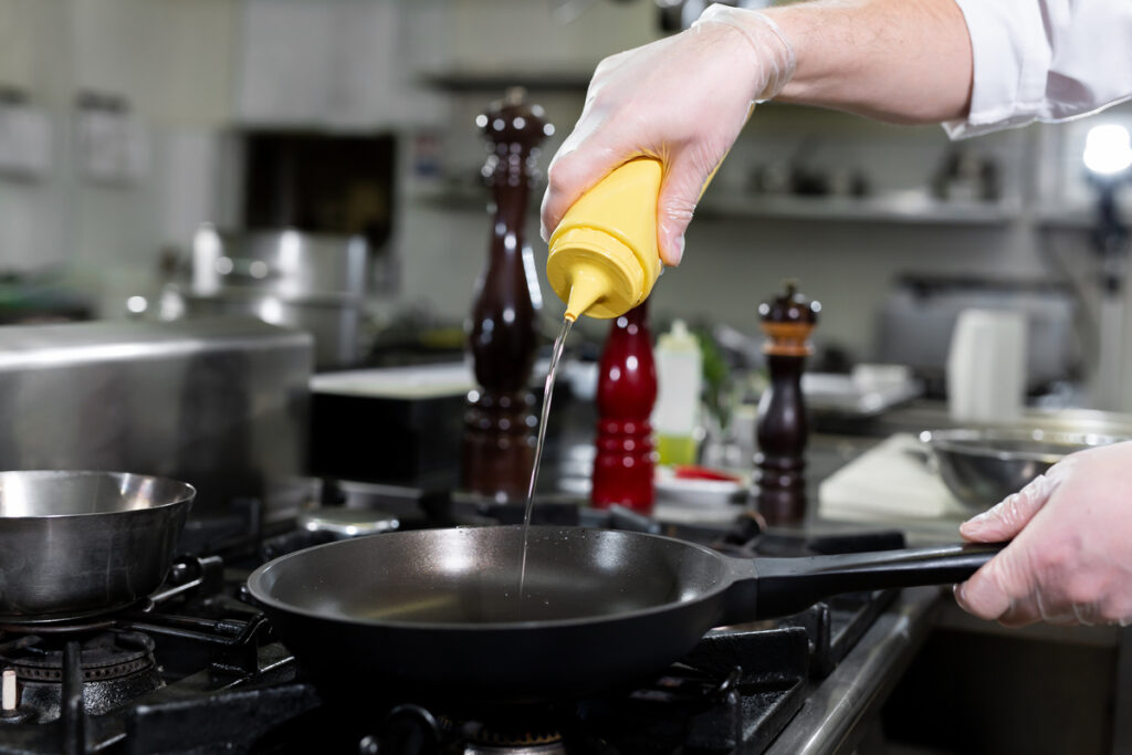 Chef pours olive oil from a bottle into a frying pan - infovzor Шеф-повар наливает оливковое масло на сковороду