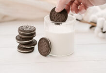 Женская рука окунает печенье Oreo в молоко