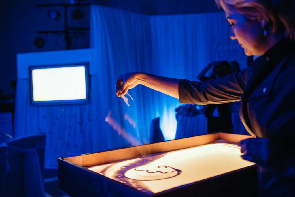 Художник рисует картины песком
