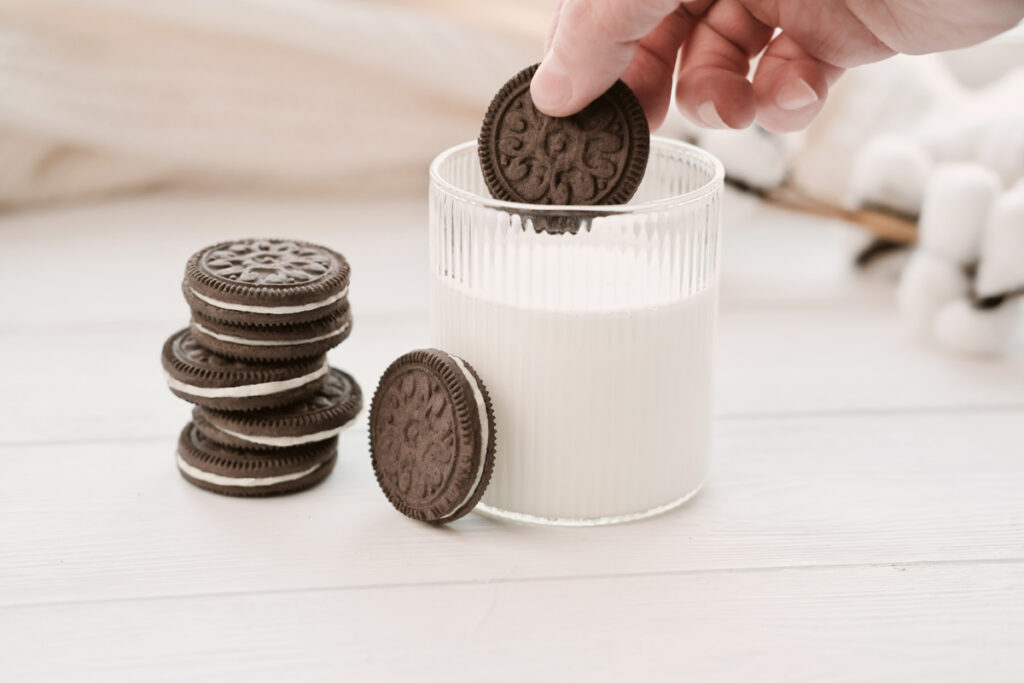 Женская рука окунает печенье Oreo в молоко
