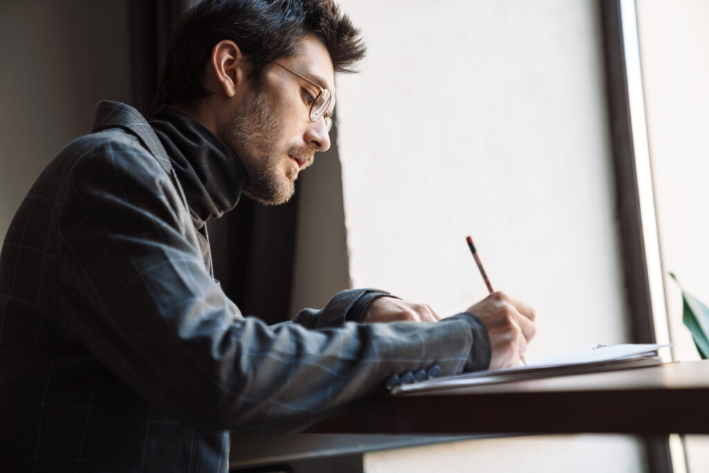 Молодой человек что-то записывает в тетрадь
