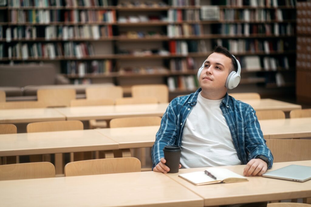 Студент слушает музыку в библиотеке
