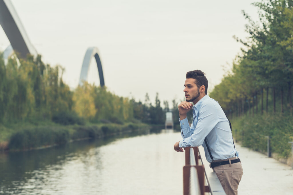 Мужчина задумчиво стоит у реки