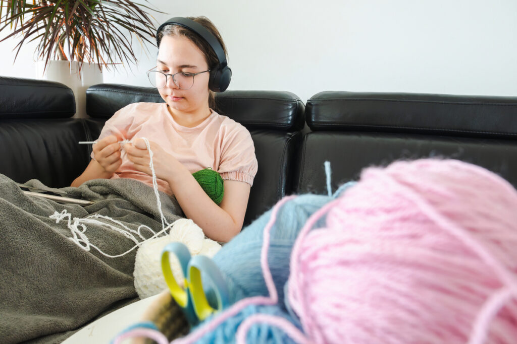 Девочка-подросток вяжет дома