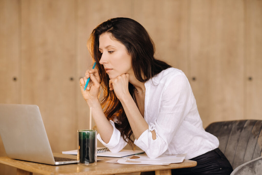 Девушка сидит за письменным столом в офисе и работает