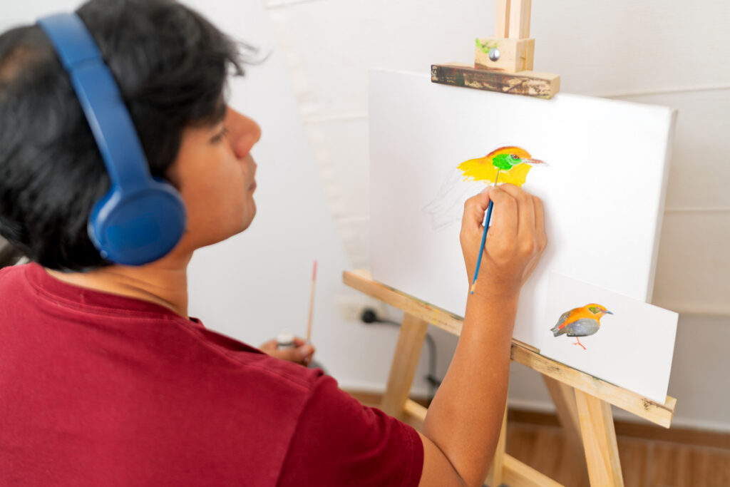 Художник рисует красочную птицу на холсте