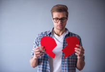 Парень держит разрезанное картонное сердце в руках