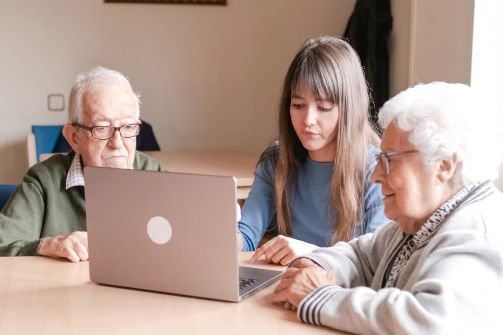 Счастливая внучка учит пожилых людей пользоваться ноутбуком