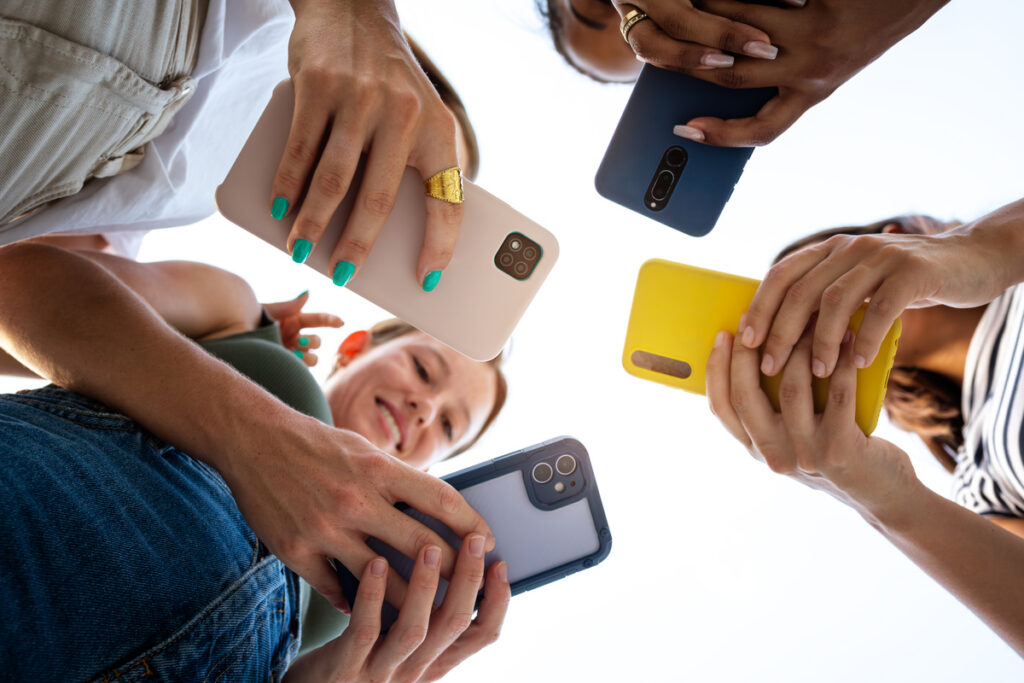 Вид четырех подруг, использующих телефоны