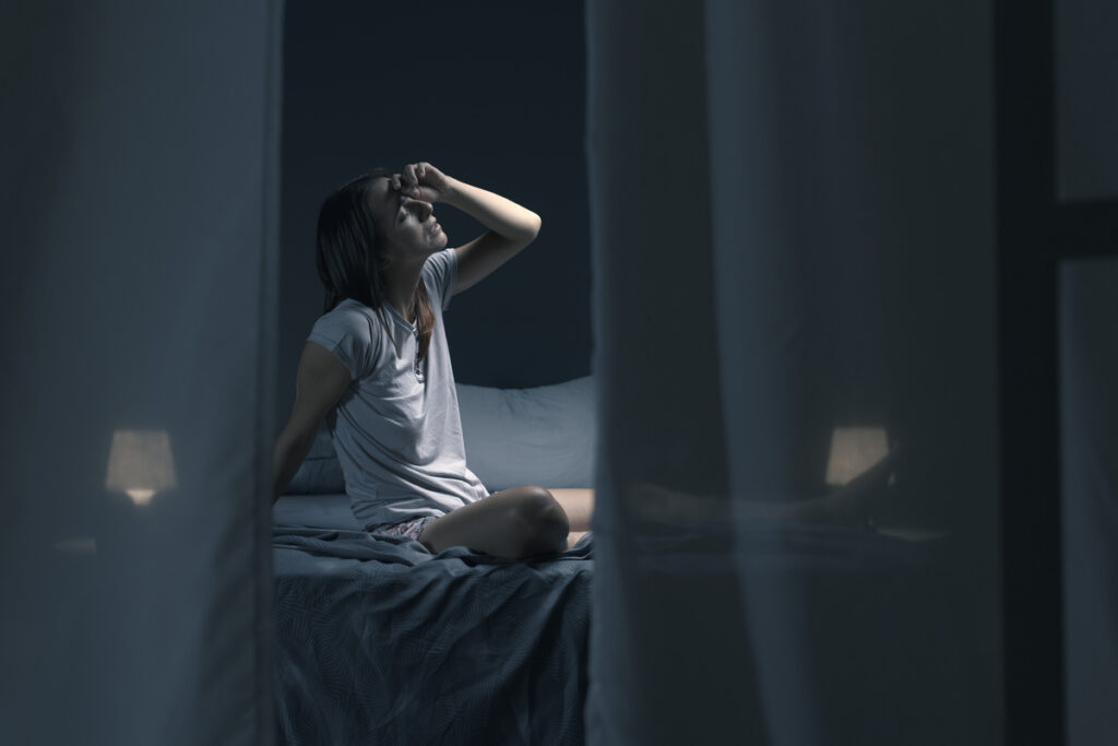 Девушка сидит ночью на постели