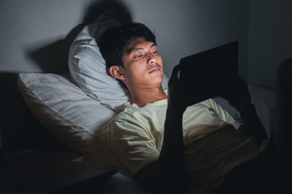 Мужчина, использующий планшет в постели ночью