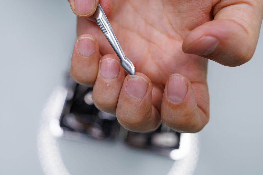 Мужчина очищает ноготь