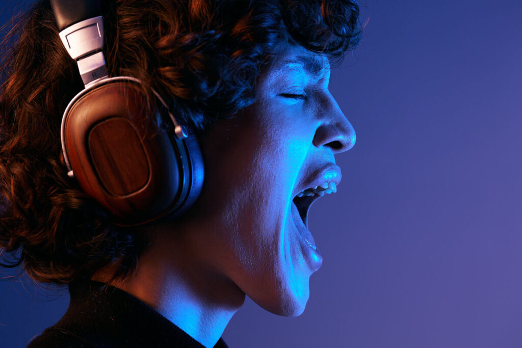 Мужчина в наушниках, слушающий музыку и поющий с открытым ртом