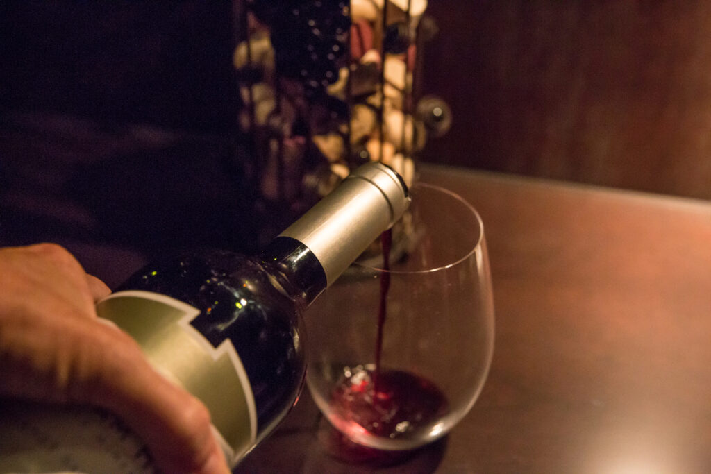 Женщина наливает красное вино