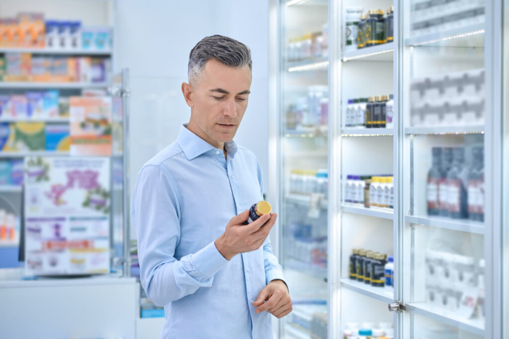 Мужчина выбирает лекарства в аптеке