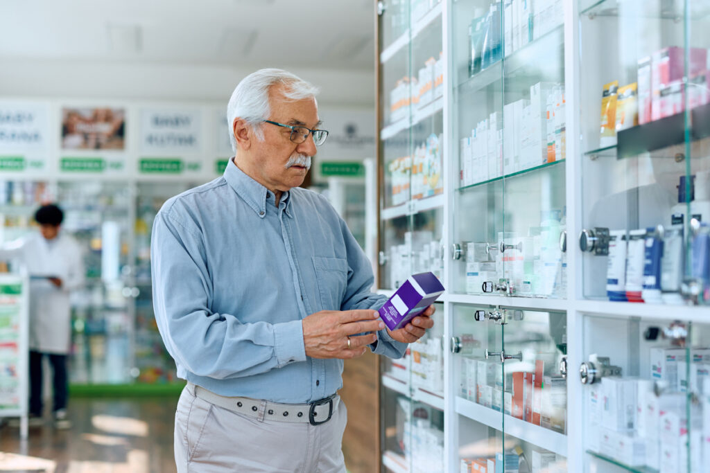 Пожилой мужчина, покупающий лекарство в аптеке