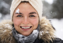 Уход за кожей в зимнее время Молодая женщина наслаждается снегом