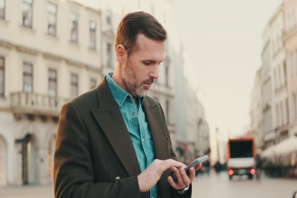 Мужчина средних лет, использующий карты на телефоне