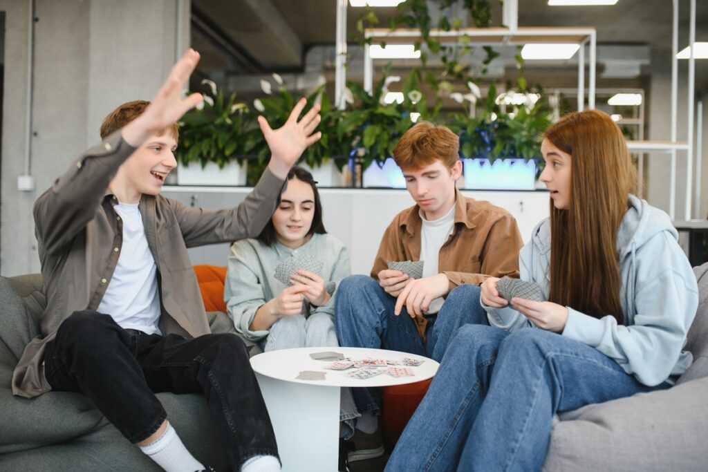 Счастливые друзья играют в карты и веселятся вместе