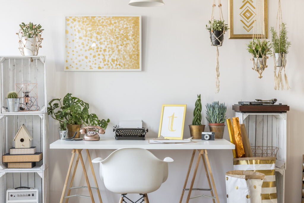 Уютное рабочее место с растениями, лампой и картинами на стене