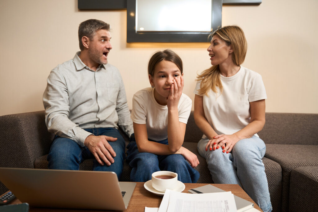 Маленькая девочка сидит на диване с родителями