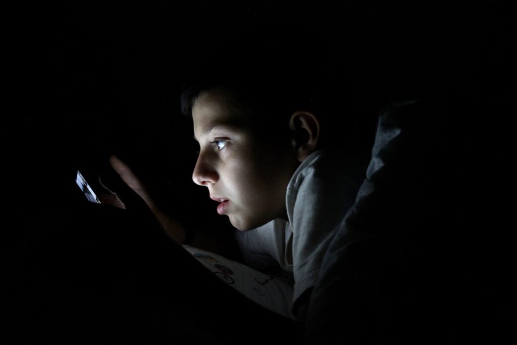 Мальчик перед сном смотрит в телефон