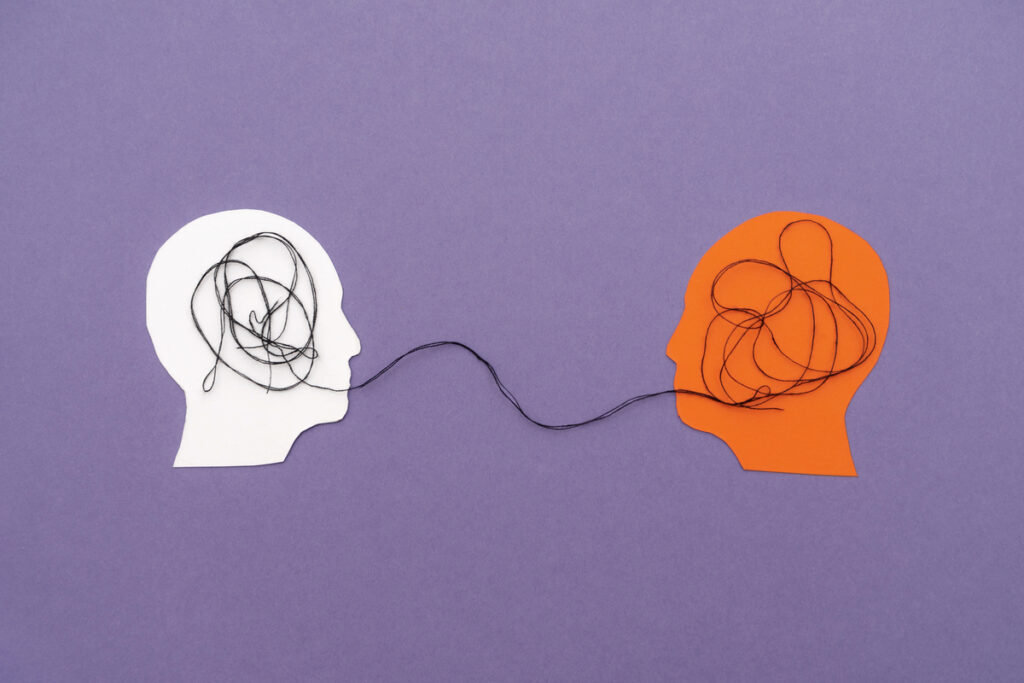 Два бумажных силуэта голов, соединенных черной нитью