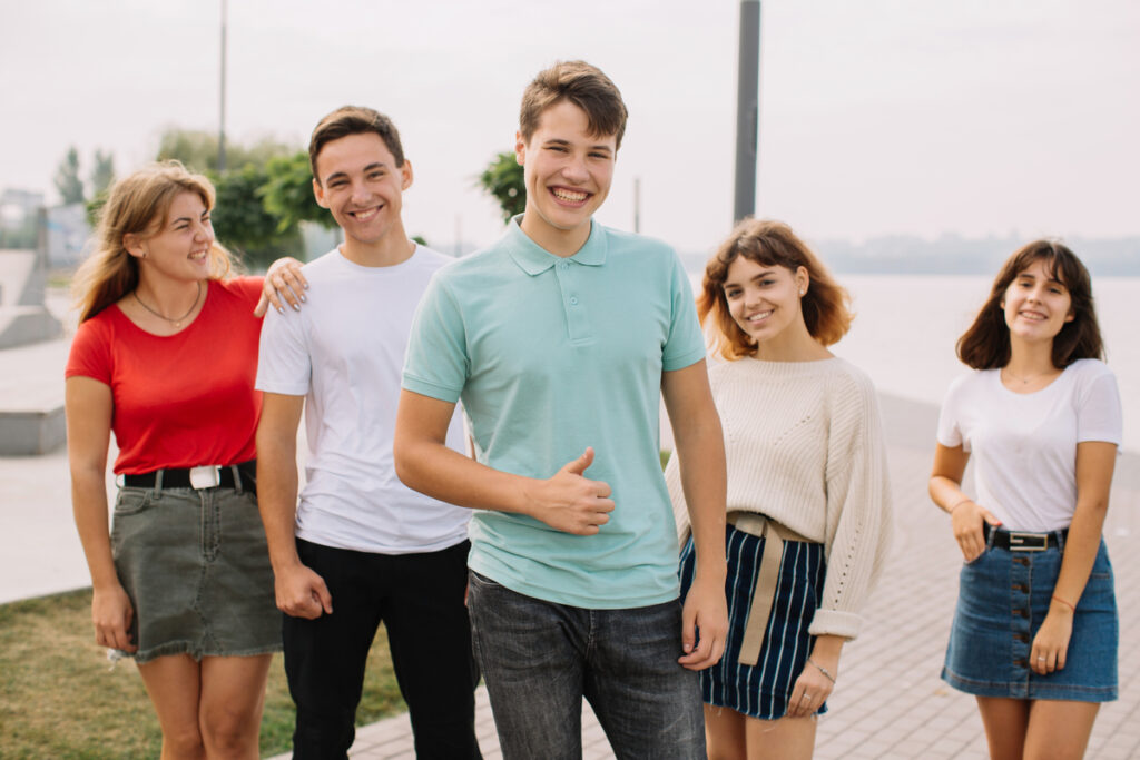 Группа улыбающихся подростков отдыхает на улице