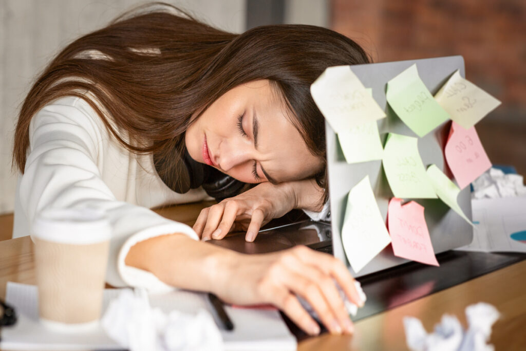 Молодая женщина спит перед ноутбуком