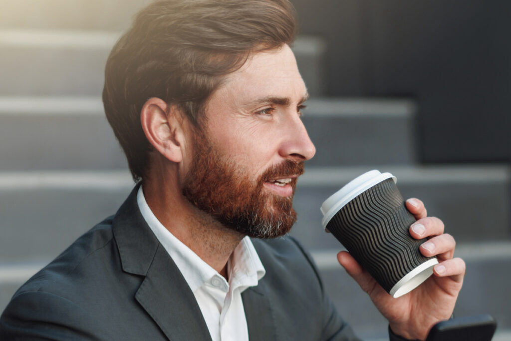 Офисный работник пьёт кофе из термокружки
