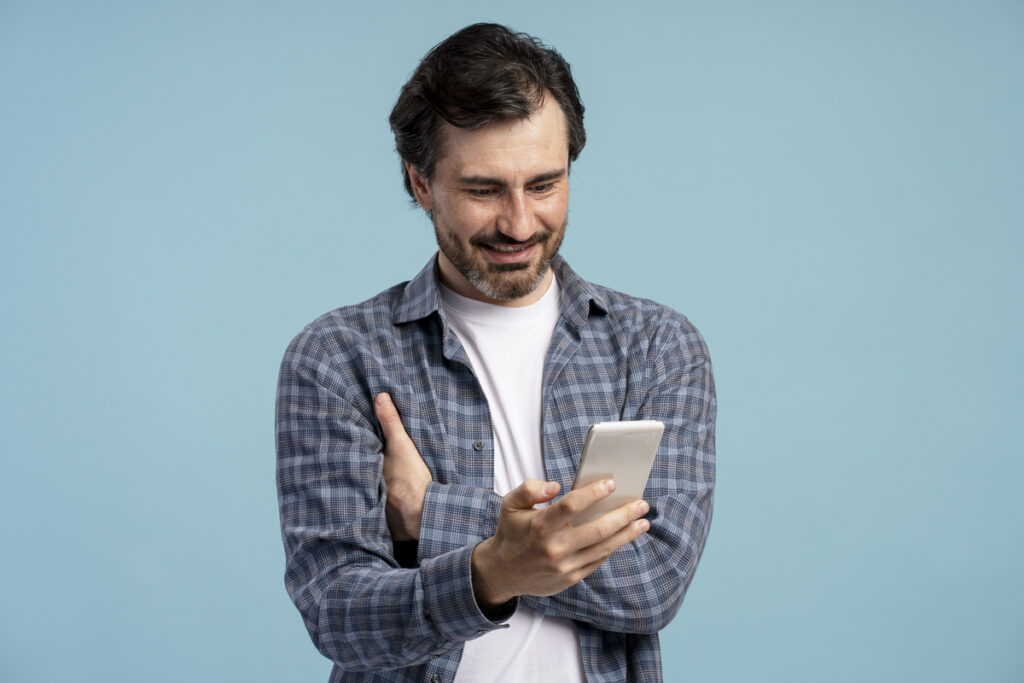 Улыбающийся мужчина смотрит видео на смартфоне