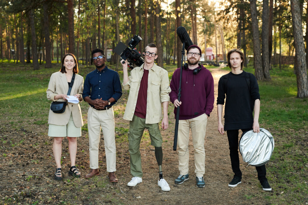 Большая группа видеооператоров с оборудованием стоит в лесу