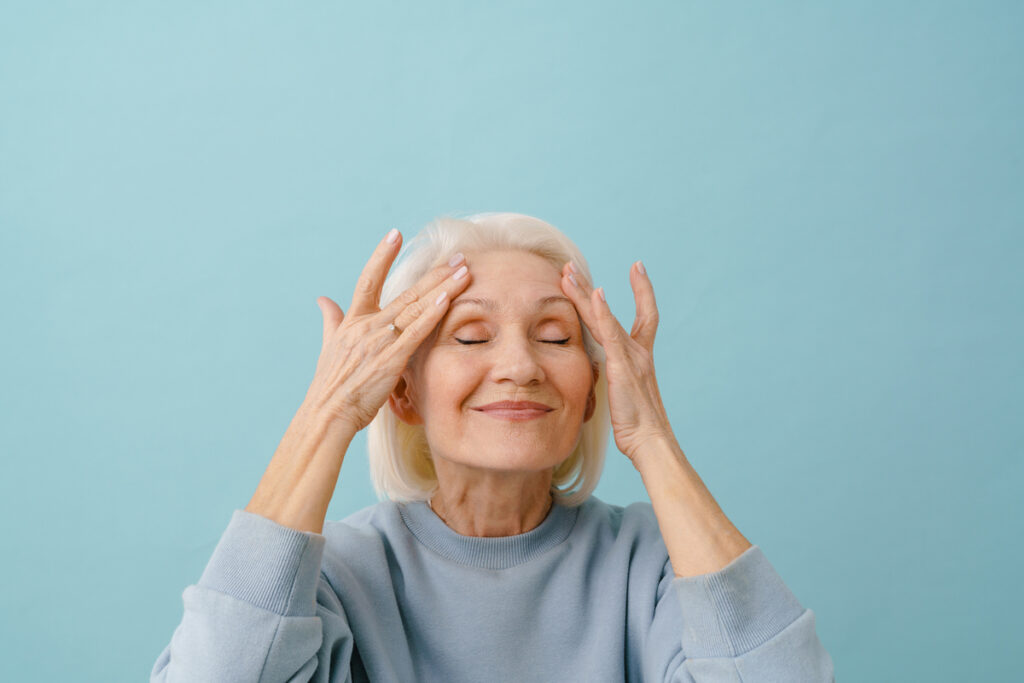 Пожилая женщина массирует виски