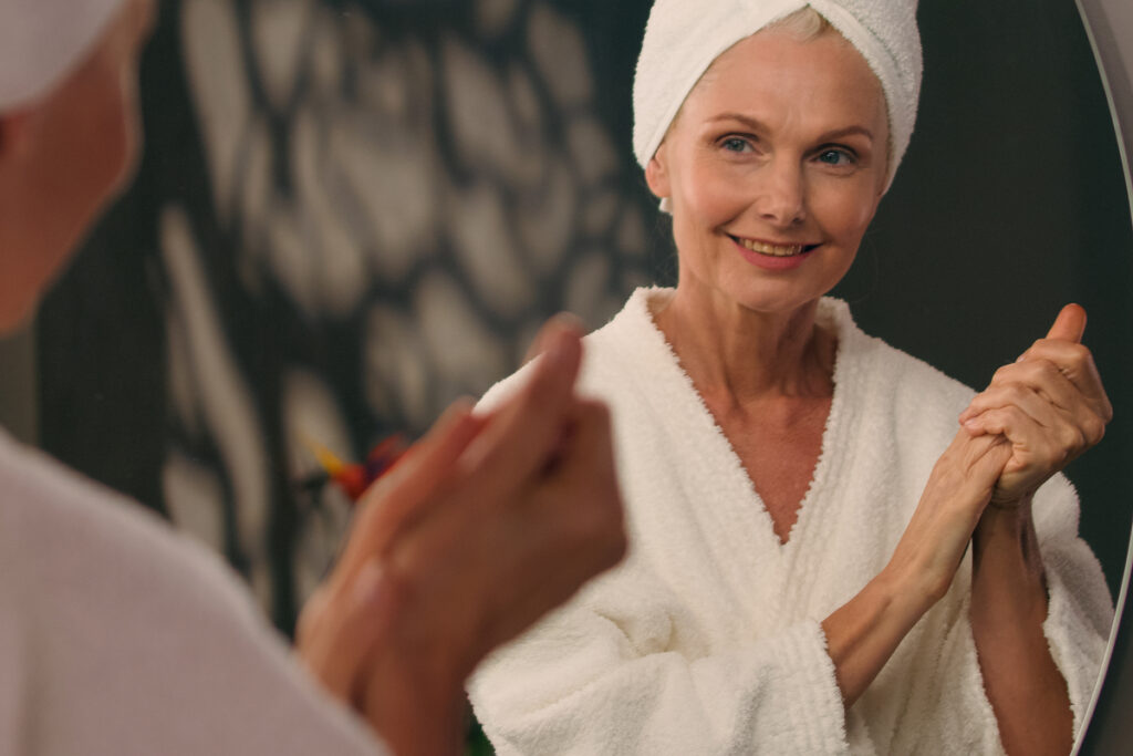 Зрелая женщина наносит лосьон перед зеркалом