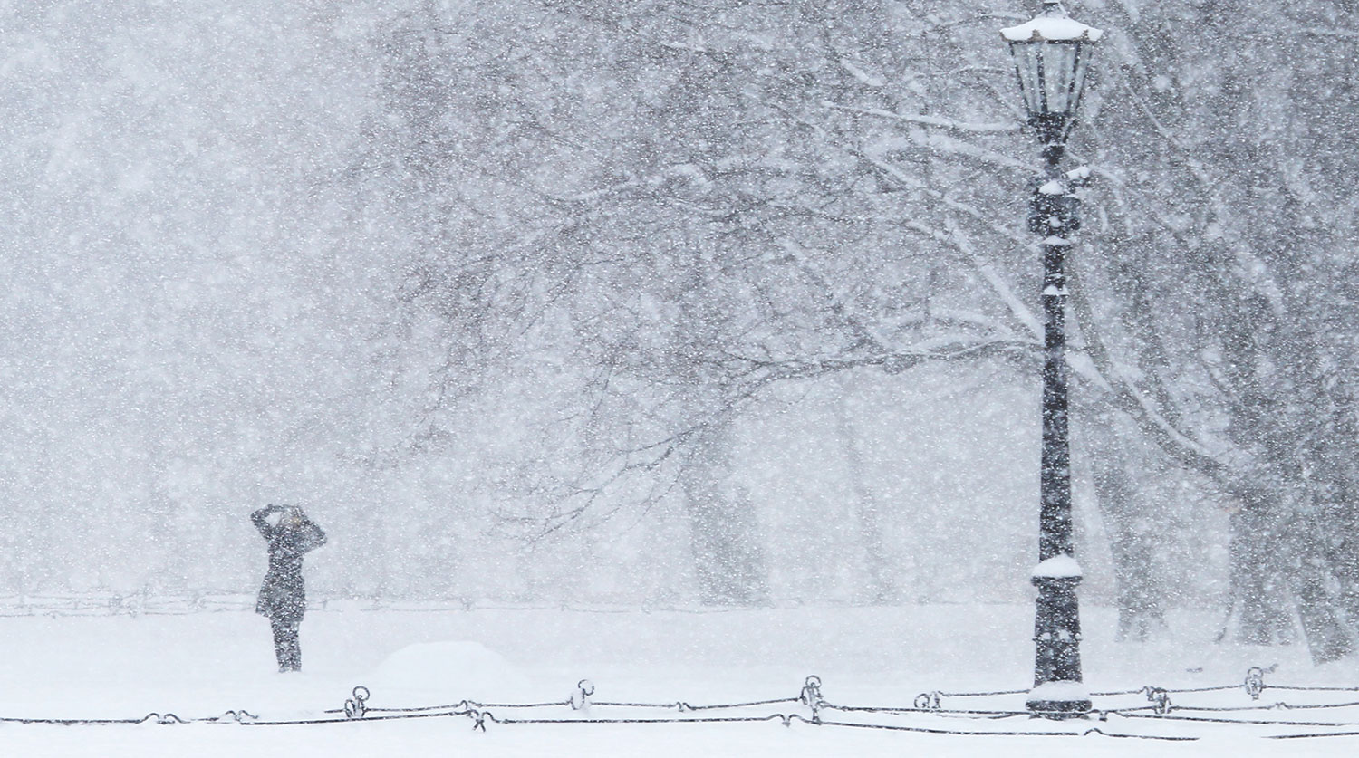 Snowstorm. Girl in the city park. Heavy snow in the city Park. Winter background.
