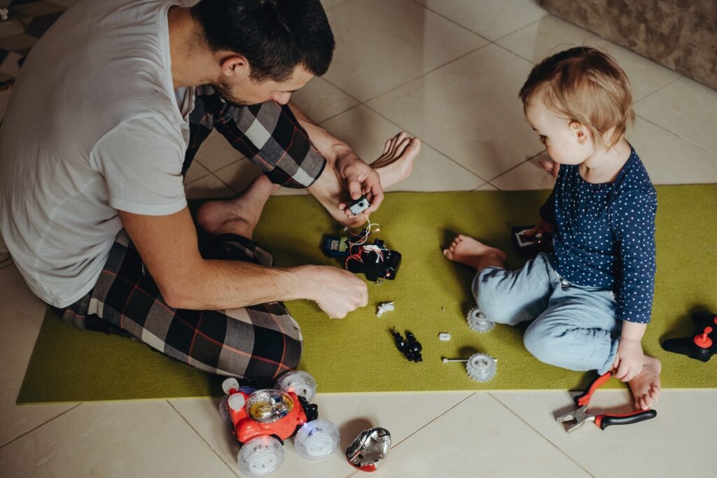 папа чинит с ребенком машинку на радиоуправлении