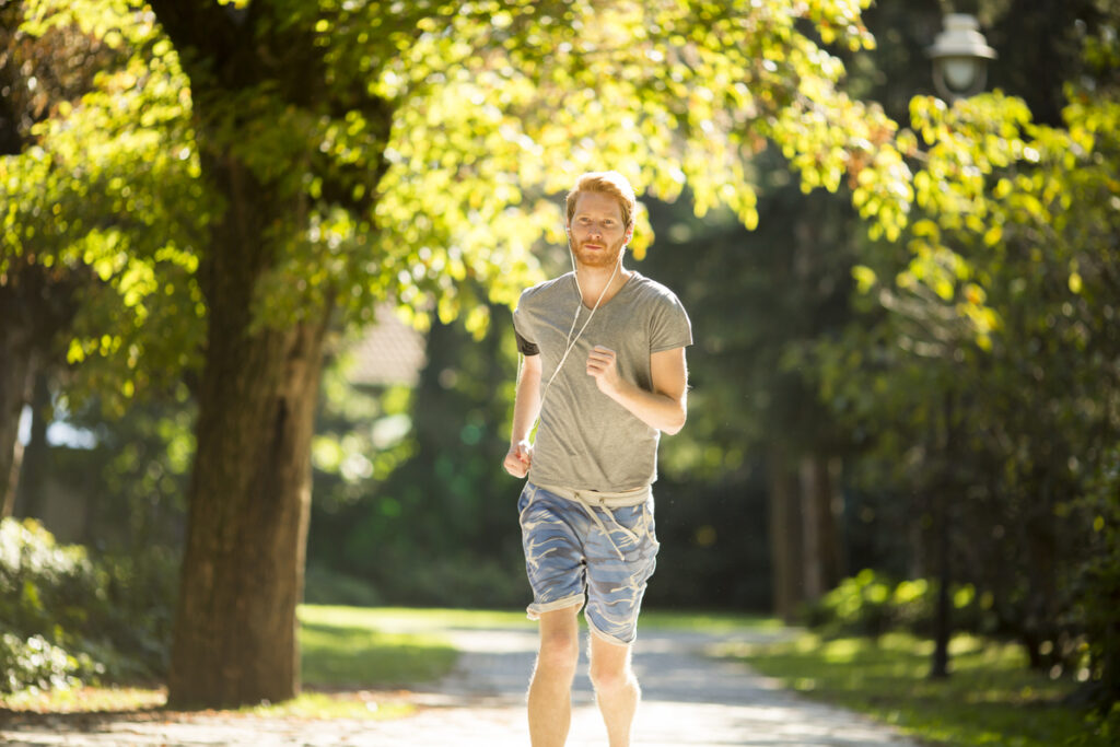 Молодой человек бежит в осеннем парке