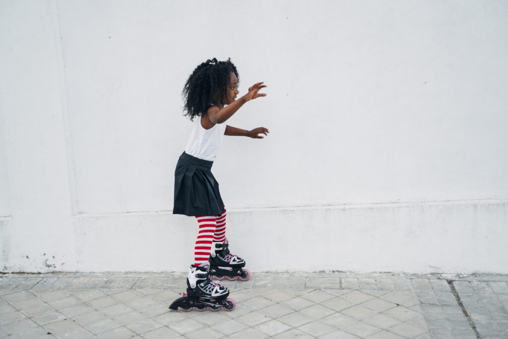 Маленькая девочка катается на роликах на улице