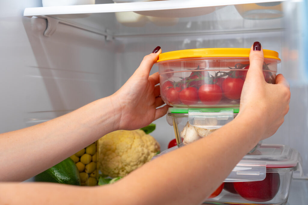 Женские руки достают контейнер из холодильника