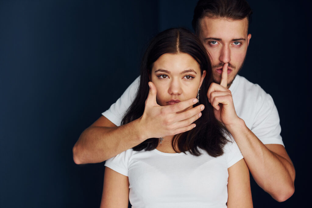 молодой человек закрывает рот девушке