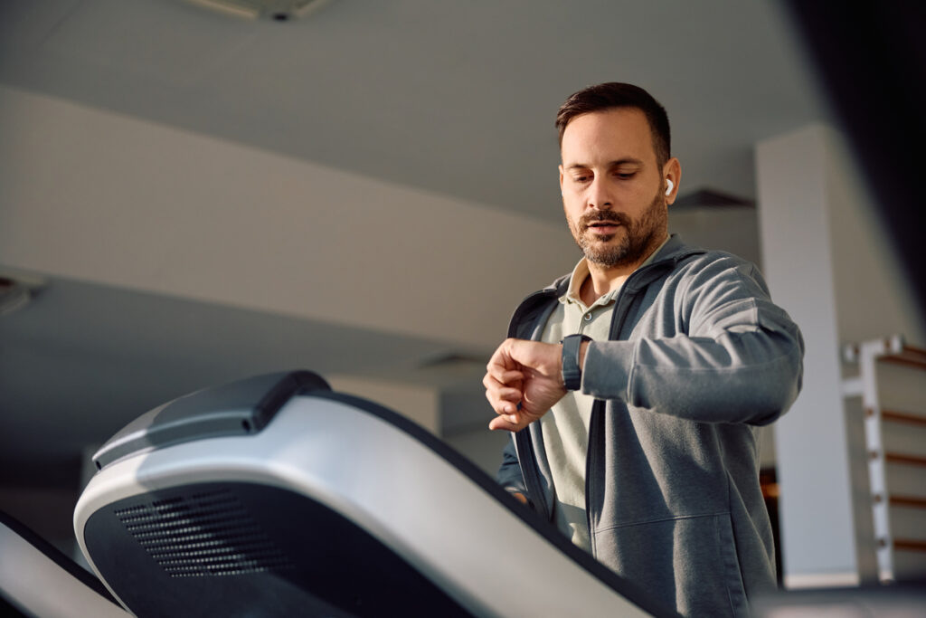 Мужчина на беговой дорожке смотрит на часы
