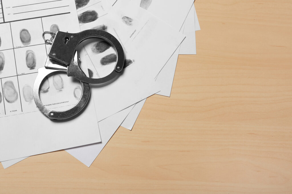 Полицейские наручники и карточка с отпечатками пальцев преступника