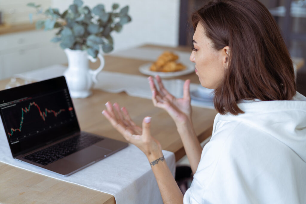 Женщина смотрит на ноутбук с финансовыми графиками